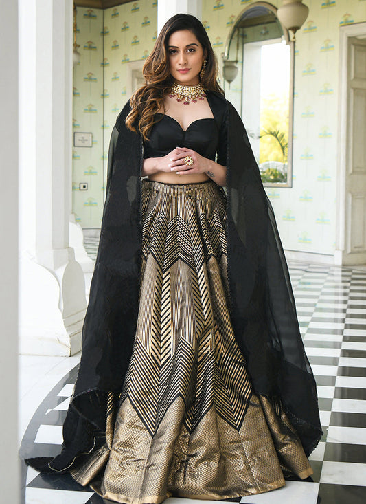 Dramatic black and gold lehenga choli, perfect for a statement-making party look. The outfit features intricate woven zari embellishments on luxurious Banarasi jacquard fabric.